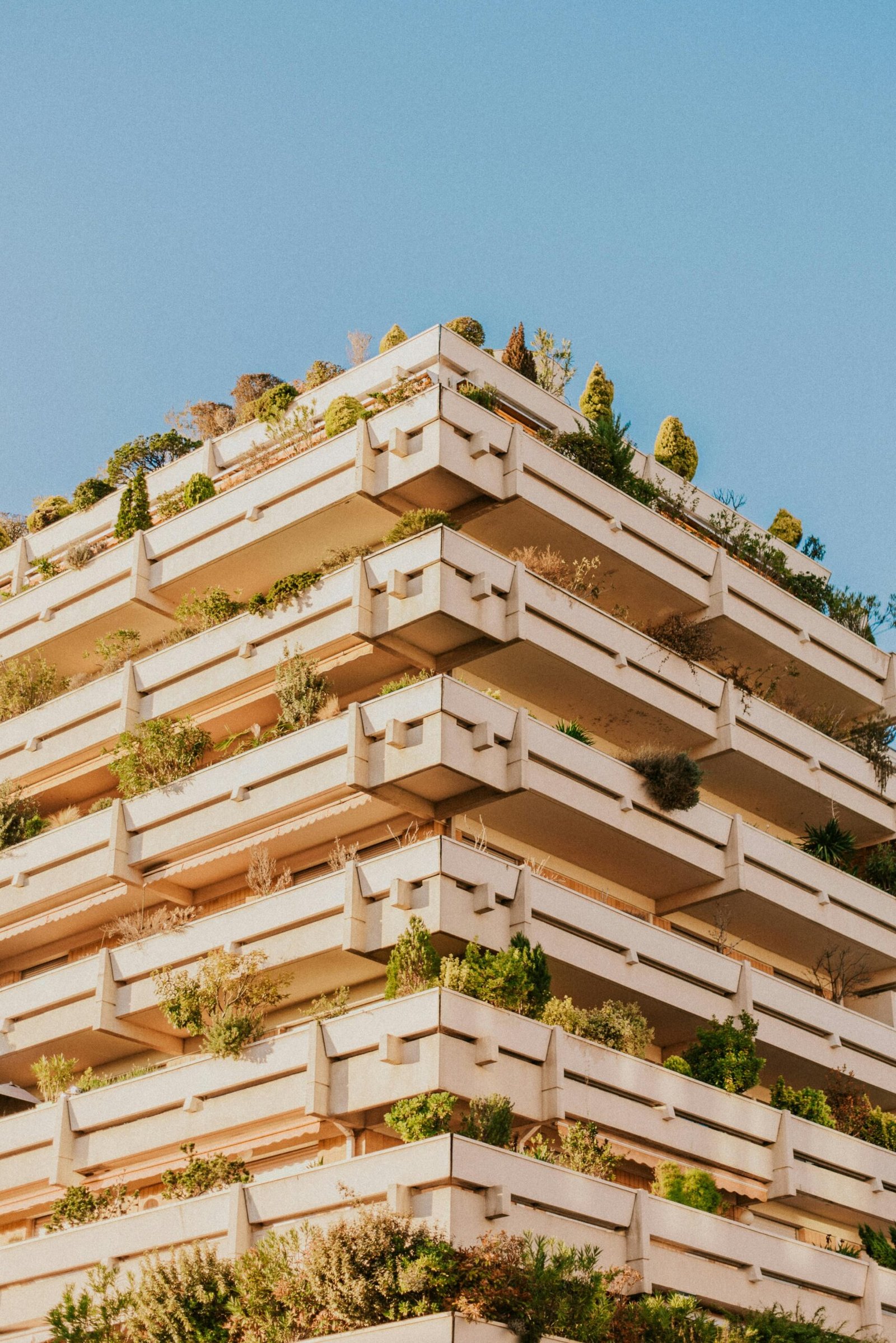 A modern building in Toulouse showcases green architecture with lush balconies filled with plants.